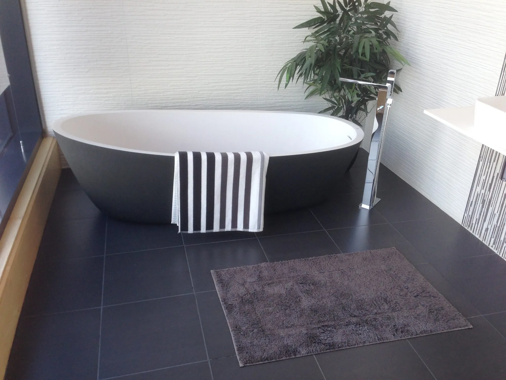 Freestanding bathtub on a dark tiled floor