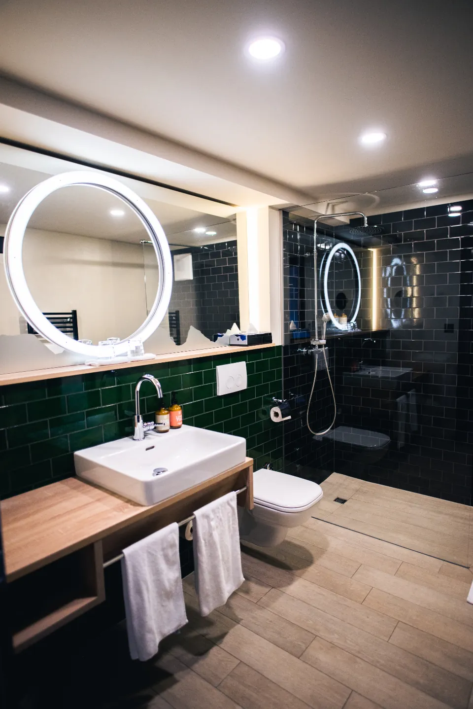 Bathroom with a round lit mirror and fresh towels